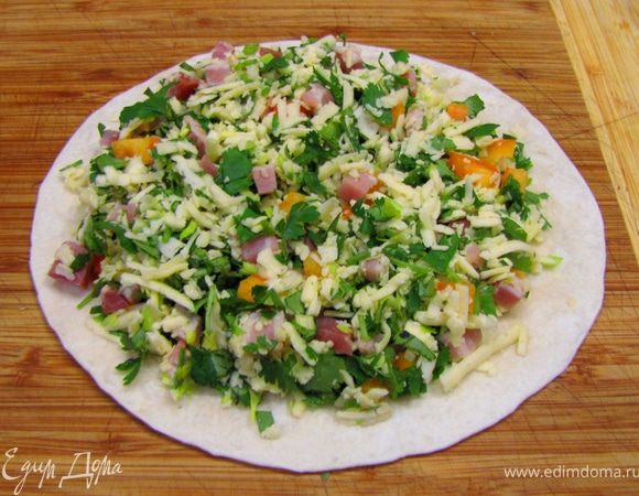 Возьмите одну тортилью. Выложите сверху четверть начинки. Обязательно оставьте по сантиметру зазор на тортилье, иначе начинка будет высыпаться. Накройте второй тортильей и слегка прижмите, чтобы начинка уплотнилась.