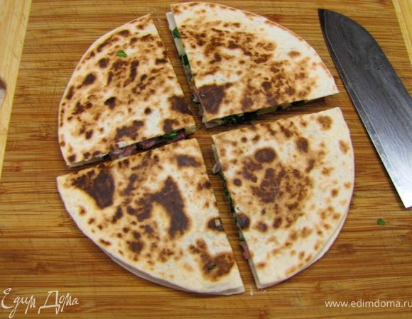 Сыр успевает прогреваться и в общем-то должен слипить всю начинку и тортильи. Выложите тортильи на доску и разрежьте каждую на четыре части.