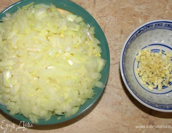 Снимите кожу с помидор в собственном соку. Для этого разрежьте кожу помидор и просто выдавите их.
Очистите и мелко порежьте лук и чеснок.