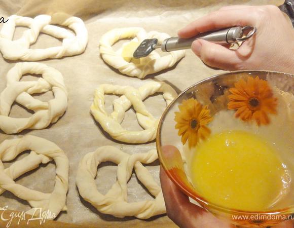 Противень застелите пергаментной бумагой. Выложите жгуты придавая форму кренделя.
Желток разведите немного водой и смажьте каждый крендель.Поставьте  противень в разогретую заранее до 200 градусов духовку. Крендельки выпекайте 15-20 минут.
