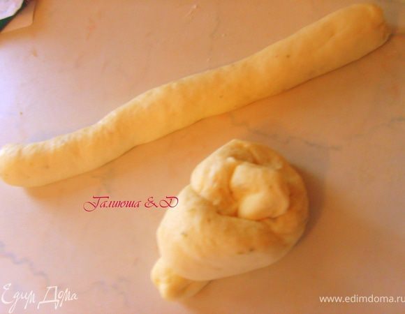 Выложить на присыпанную мукой поверхность, вымесить и разделить на 8 примерно одинаковых шариков. Каждый шарик скатать в колбаску длиной около 25 см, завязать узелком 