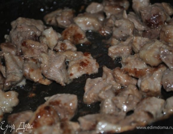 Мясо нарезать маленькими кусочками, обвалять в муке и обжарить на сильном огне до корочки. Переложить в кастрюлю. 
Обжарить лук и отправить его к мясу.