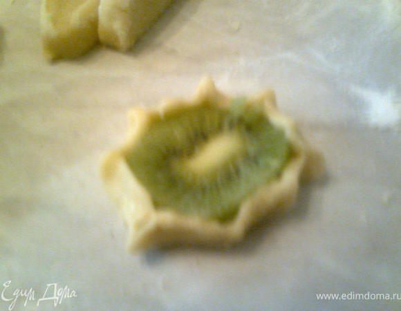 Тесто разделить на кусочки, из каждого кусочка сформировать лепешечку, уложить на нее киви, защипить края.