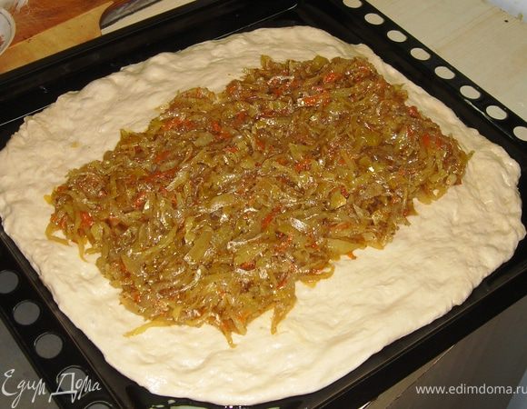 Когда тесто подошло, берём противень большой, смазываем его растительным маслом и выкладываем на него наш ком теста.
Там сразу и раскатываем тесто в пласт толщиной 5-7мм.
В центр выкладываем по всей длине начинку.