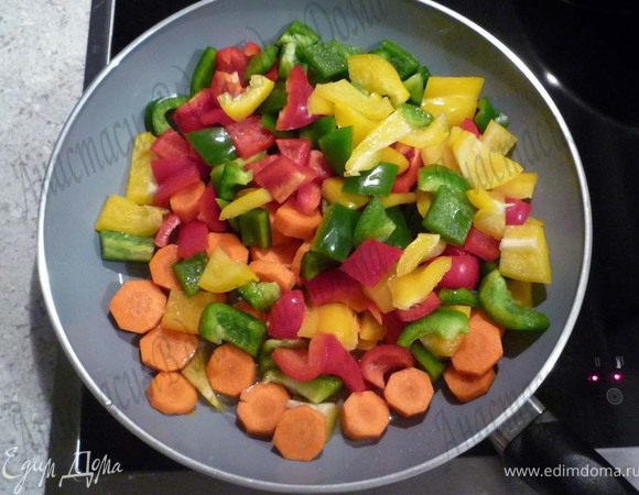 Вскипятить овощной бульон и рис, накрыть крышкой и на среднем огне тушить 20 минут. Перец помыть, почистить, нарезать небольшими кусочками. Морковь почистить и нарезать кольцами. Обжарить перец и морковь в 1ст.л. масла в течение 5 минут.