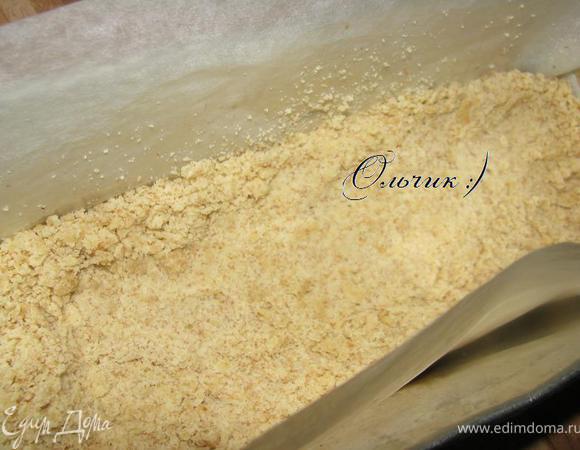 Застелить форму пергаментной бумагой, выложить половину теста, немного примять дно, чтобы остались невысокие бортики.