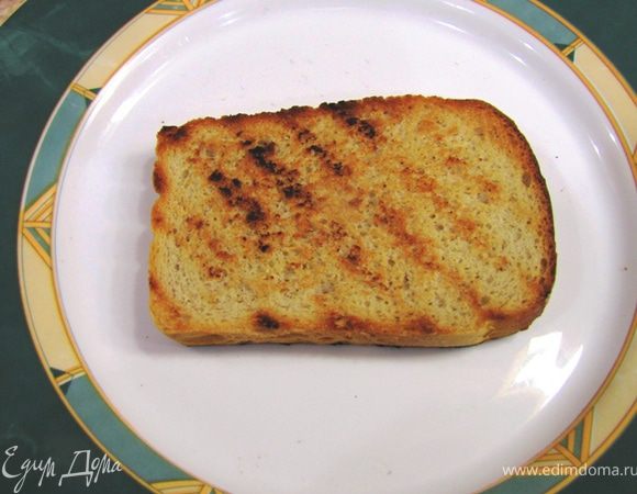 Тем временем сделайте брускетты из хлеба. Нарежьте хлеб на ломтики и обжарьте их на сильном огне на гриле. У меня - специальная сковорода гриль. Натрите их оставшимся целым зубчиком чеснока.