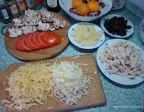 Для топпинга отварите курицу. Затем порежьте и разделите ее по волокнам. Маслины порежьте на кольца. Грибы пластинками. Помидоры кружечками. Кольца ананаса кубиками. Твердый сыр и моцарелла натрите на крупную терку.  