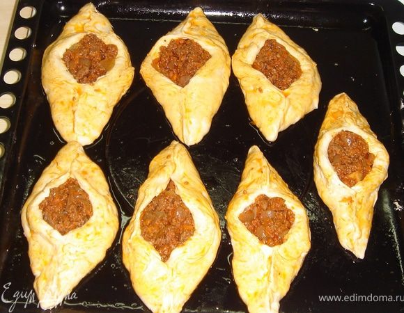 Итак, тесто подошло…Тесто зрительно делим на 9-10 частей. Отрываем кусочек теста, обмакиваем его в небольшом количестве муки и разминаем из него круг. В центр кладём полную с горкой ст.л. начинки и защипываем с двух сторон тесто.
Каждый расстегайчик смазываем подливой от пережарки фарша.
