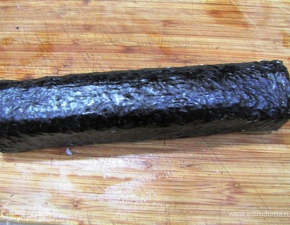 Старайтесь заворачивать ролл как можно плотнее. Придание роллу квадратной формы дает дополнительное уплотнение последнего. С торцов начинка с рисом может слегка вываливаться. Аккуратно пальцами поправьте торцы и сделайте их ровными. Так как риз у вас липкий, проблем с этим не будет.
Отставьте ролл в сторону, чтобы нори полностью пропиталась жидкостью и стянуло ролл в плотный цилиндр.