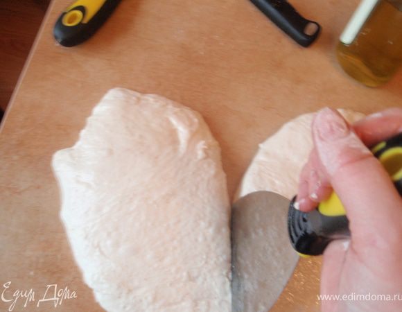 Аккуратно вынуть тесто на смазанный растительным маслом стол так чтобы не смять его.Разделить шпателем на 4 удлиненных куска(шпатель - это важно.Им удобно делить тесто не сминая его.Нажал и отодвинул в сторону.Все пузыри должны сохраниться в тесте.