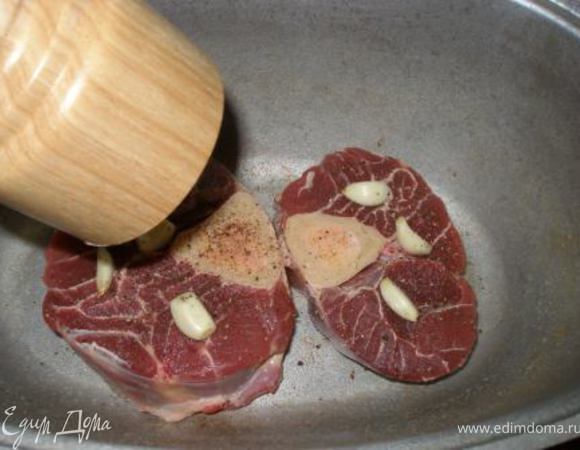 Мясо выложить в жаропрочную посуду, посолить, поперчить. Сверху выложить целые зубчики чеснока. 
