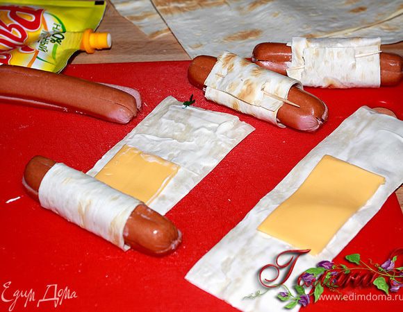 Сначала подготавливаем сосиски -
по-краям разрезаем их на 4 части
с двух сторон по 2 см.
Листы лаваша режем под размер сосисок так, 
чтобы разрезанные края выглядывали,
а длиной примерно 20 см.
Слегка смазываем лист лаваша тонким слоем майонеза,
кладем кусочек сыра (1/2 пластинки) отступив от края 6-7 см.
Сосиску заворачиваем в лаваш и закалываем зубочисткой.
Делать нужно всё быстро, т.к. листы лаваша очень быстро засыхают,
можно их положить в пакет и доставать постепенно.
Подсохший лаваш плохо закручивается и расслаивается!