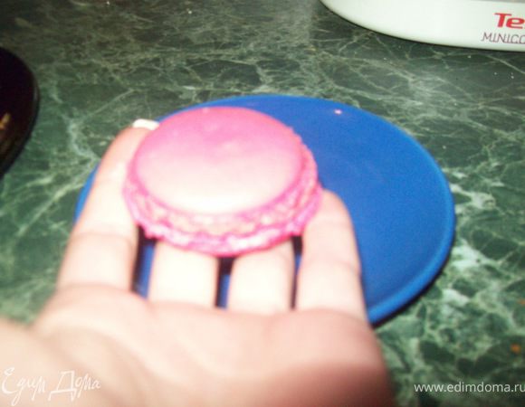 Смешать вместе сахарную и миндальную пудру. Просеять. Белки взбить в керпкую пену с солью и лимонным соком, постепенно, ложку за ложкой, добавляя сахарный песок, чтобы получилась гладкая, блестящая масса. Добавить в белки ликёр, розовую воду и 12-ть капель красного красителя. Перемешать лопаточкой. Аккуратно всыпать сахарно-миндальную пудру. Снова тщательно перемешать. Переложить в  шприц с круглой насадкой. Выдавить одинаковые окружности диаметром 4-5 см на противень, застеленный пергаментом. Ничем не накрывая оставить подсыхать макаруны минимум на 1 час. Выпекать около 10-ти минут при 150 градусах . Дверцу духовки во время выпечки не открывать! Слегка сбрызнув водой из распылителя, отделить готовые макаруны от пергамента.

Готовим ганаш. Малину при помощи пресс-пюре раздавить в кашицу. Крахмал развести в одной столовой ложке воды. В небольшой толстостенной кастрюльке смешать хорошо малину, сахар, крахмал и яйцо. Варить до загустения на медленном огне минут 5-ть, постоянно помешивая. Добавить ликёр. Остудить. 
Склеить половинки макарун при помощи малинового ганаша и, перед подачей, поставить на нижнюю полку холодильника минимум на 1 час (в идеале на 12 часов).