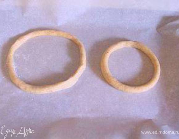 Раскатать  тесто в длинную колбаску в палец толщиной.Когда вы раскатываете тесто, используйте не муку, а сахарную пудру для присыпки рабочей повехности.
Нарезать колбаску на кусочки и сделайте кружки так, чтобы каждый следующий кружок был меньше предыдущего. Первая моя колбаска было 12 см длиной.Потом я стала прибавлять по 2 см: 14,16,18,20... и так нужно сделать 18 колбасок. У меня получилось только 15.Не хватило слегка теста.Видимо, я сделала колбаски чуть толще,чем они должны были быть.
Разложить колечки на противень покрытый пергаментом и выпекать при 200° 10 минут. Оставить расстояние между колечками, потому что они поднимутся и раздуются.