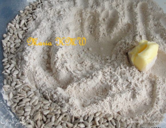 В серединку всыпаем сухие дрожжи, сахар и соль. Масло и 3 ст.л. семечек всыпаем с краю и заливаем 300 мл теплой воды.