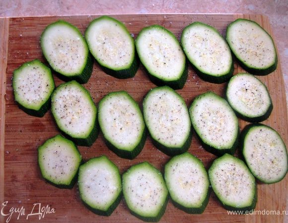 Помойте цукини и протрите полотенцем. Нарежьте наискосок на кружки толщиной 0,5 см. Выложите цукини на доску. Посолите и поперчите, посыпьте тимьяном. 