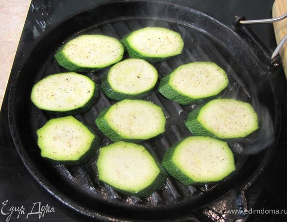 Нагрейте гриль или сковороду на огне. Смазывать маслом не надо. Нагреть надо сильно. Выложите кружки цукини стороной, смазанной маслом.