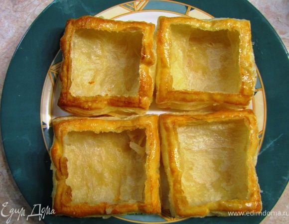 На промасленную бумагу для запекания кладем в противень тарталетки.
Печем в предварительно разогретой до 180 градусов духовке в течение 25-30 минут.
Достаем тарталетки.
Прорезаем по швам верхнюю часть теста и выбираем до половины внутри.