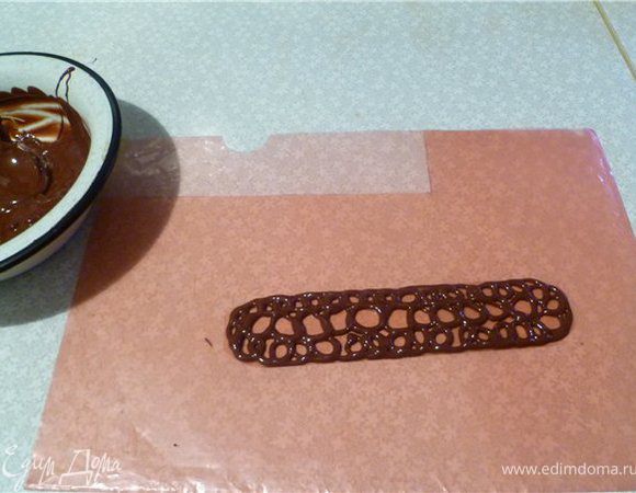 Для украшения шоколад растопить на водяной бане. Для банта: файл для документов разрезать на полоски, нанести на них с помощью кондитерского мешка шоколад, соединить концы прищепкой. Положить в морозилку до застывания. Для банта нужно 9 полосок. Для узора: нарисовать узор на пергаментной бумаге, обвести шоколадом, дать немного застыть и перенести на торт. Положить в холодильник, минут через 15 можно снять бумагу. 