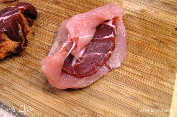 Положите ломтик копченого мяса в грудку и сложите грудку.
