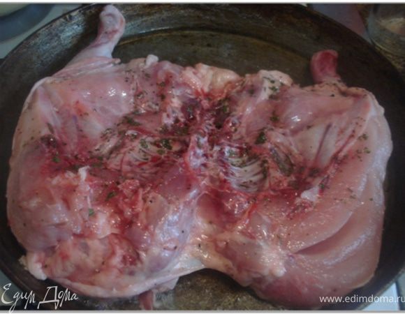 В большой чугунной сковороде разогреть растительное масло, положить цыпленка спинкой вниз и поставить сверху груз. Жарить примерно 20 минут.