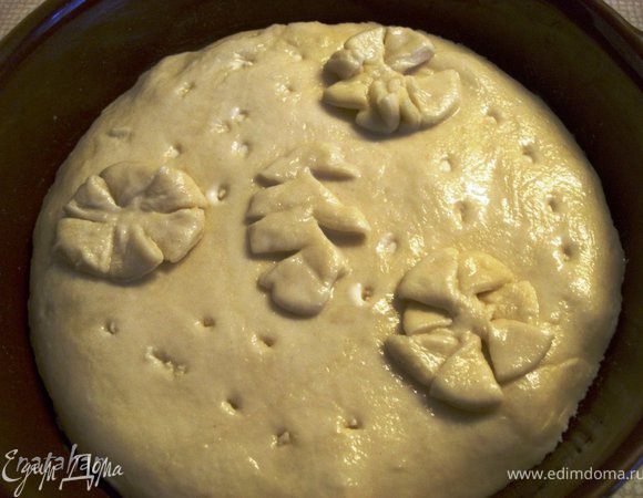 Остатки теста собрать, скатать их в шар и разделить на две части: на маленькую пиццу (пока положим в морозильник) и на оформление Quarkkuchen. Сделать цветочки-листочки и положить их на смазанную молоком верхушку пирога. Цветочки-листочки также смазать молоком. Наколоть верхушку пирога вилкой.