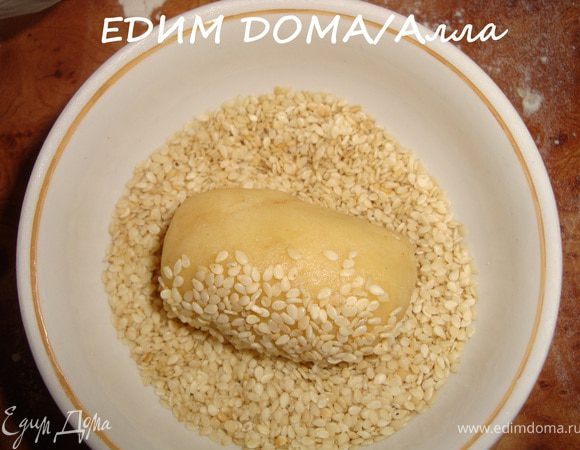 Теперь берем кусочек теста и "замуровываем" в него финик (курагу) с орешком. Выкатываем полученную "колбаску" в кунжутном семени.