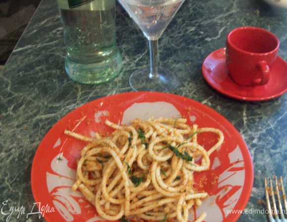  Духовку предварительно разогреть до 200°С. 
Спагетти отварить в подсоленной воде!) 
Хлеб поломать, выложить в небольшой противень и отправить в разогретую духовку на 10 минут. Цедру  натереть на мелкой терке
 Поджаренный хлеб, чеснок, цедру, вяленые помидоры и сладкую паприку поместить в блендер, добавить 1 ст. ложку оливкового масла, посолить, поперчить и измельчить все в крошку. 
Петрушку мелко порубить. Горячие спагетти сбрызнуть оливковым маслом, перемешать, присыпать пряной сухарной крошкой и петрушкой.
