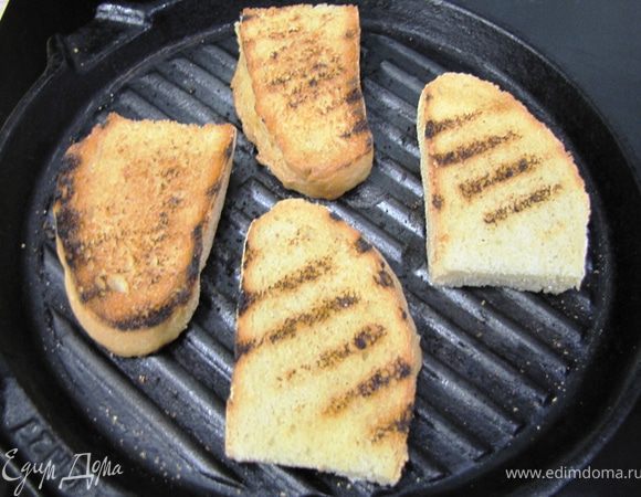 Отрежьте 8 ломтиков хлеба, толщиной 1 сантиметр. Я отрезал от своего хлеба 4 ломтя и потом разрезал их пополам.
Обжарьте их на гриле до появления полос.
Немного остудите и натрите со всех сторон чесноком.