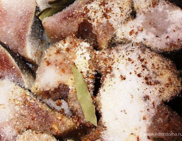 Тушки сельди помыть и порезать на 1.5 см кусочки. Сложить их в маленькую кастрюльку или мисочку. Лавровые листья поломать на 3-4 частицы и положить между кусочками рыбы.  Посыпать сверху хмели-сунели, сухой чеснок, сахар и соль.