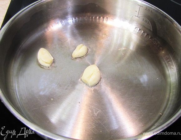 В разогретую сковороду с растительным маслом положите зубчики чеснока не нарезая их. В таком виде они довольно хорошо отдадут вкус и при этом не пережарятся. К тому же жаренный чеснок будет очень вкусен.
Жарьте чеснок около минуты, чтобы он стал слегка золотистого цвета.
Огонь должен быть средний.