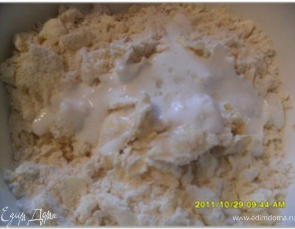 Добавить орехи, кефир и миндальную эссенцию. Хорошо перемешать вилкой, а затем руками; должно получиться рассыпчатое тесто комками равномерной влажности.