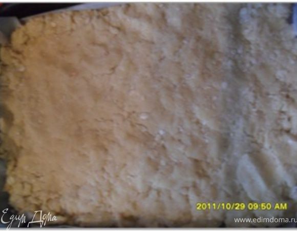 Отложить 1 чашку теста и смешать с кокосовой стружкой. Остальное тесто выложить на смазанный противень и плотно прижать ко дну.