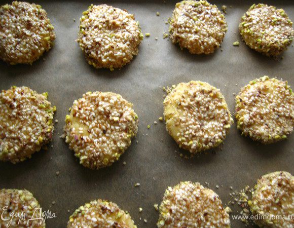 Все надо делать быстро, пока мед теплый!( если остынет, подогреть в микро) Берем печенюшку, одной стороной обмакиваем в мед с кунжутом, вторую сторону в орехи. Бока тоже прокатываем в ореховой смеси. укладываем на противень.