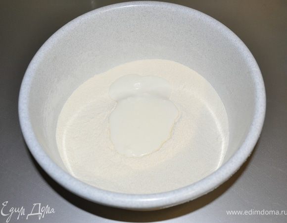 В сухой массе делаем углубление вливаем туда сметану. И начинаем вымешивать тесто. 