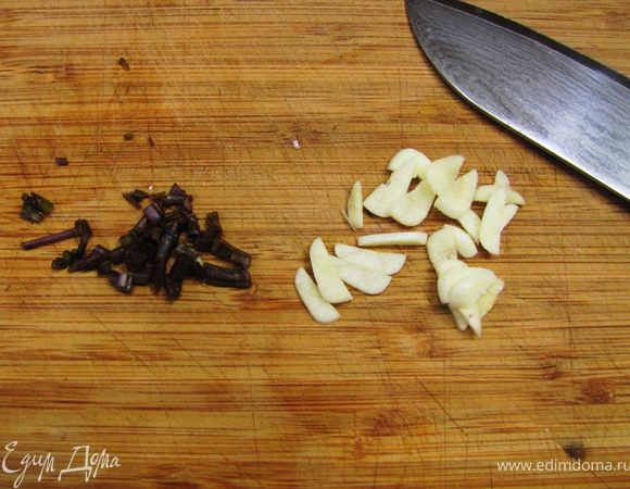 Если у вас свежие мидии, хорошо промойте их, подержите в воде, чтобы ушел песок, затем еще раз тщательно промойте, соскоблите все наросты и выбросьте те раковины, которые не раскрыты. Возьмите большую глубокую сковороду или кастрюлю. Нагрейте в ней оливковое масло. Порубите зубчик чеснока и стебли базилика. Еще раз говорю, на фотографии у меня мало базилика. Лучше всего брать зеленый базилик — 4–5 веточек. Учтите, что чеснок не должен быть сильно обжарен. Цвет должен стать слегка золотистым, иначе он сильно испортит вкус всего блюда.