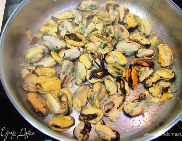 Через тридцать секунд увеличьте пламя и бросьте мидии в сковороду. Если у вас свежие мидии, рекомендую плеснуть полстакана белого сухого вина и накрыть крышкой. Если нет, крышкой накрывать не надо. Энергично встряхивайте сковороду, чтобы мидии не прилипли.