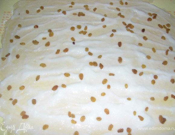 Подошедшее тесто слегка посыпать мукой, вынуть из чашки и ещё раз вымесить.
Тесто разделить пополам.
Каждый кусок раскатать в прямоугольник,смазать пудингом и присыпать изюмом.
