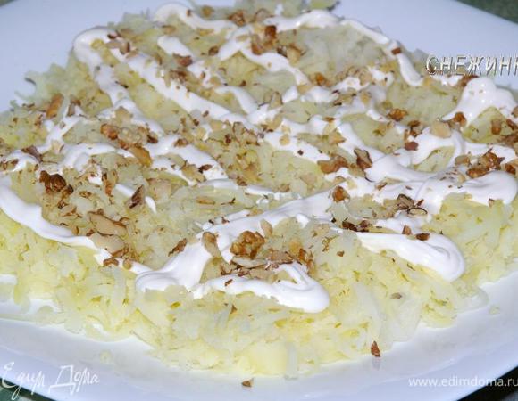 Теперь укладываем слоями. Вначале натираем на терке картофель. Делаем майонезную сеточку, немного посыпаем орешками.
