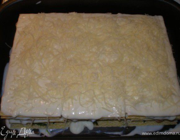 Накрываем тестом, поливаем соусом (используем весь, что остался) и посыпаем пармезаном. Обратите внимание, соус должен покрывать всю поверхность лазаньи.