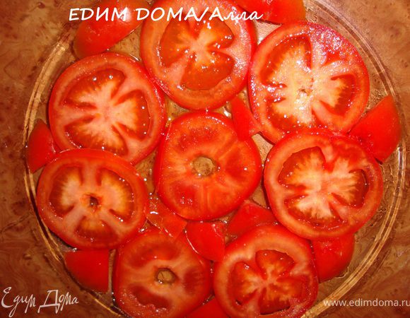 На дно формы, в которой будем запекать рыбу налить 1 ст.л. оливкового масла. Помидоры помыть и порезать кружочками. Выстелить дно смазанной формы кружочками помидоров.