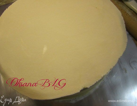 Меньшую часть мастики перенести на верх торта, аккуратно обрезать края. Верх немного смочить водой.