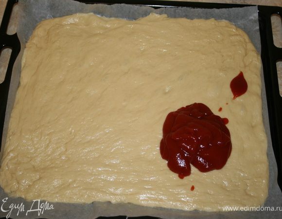 Раскатать тесто на противне, я использовала пергамент, можно просто присыпать мукой, но главное не делать на растительном масле, получается очень жирно. Сверху размазать томатную пасту, вкуснее всего, если ее делать самим, потушив на сковороде в оливковом масле томаты без кожицы с добавлением чеснока, орегано и базилика. Но я все делала на скорую руку, поэтому кетчуп из бутылки.