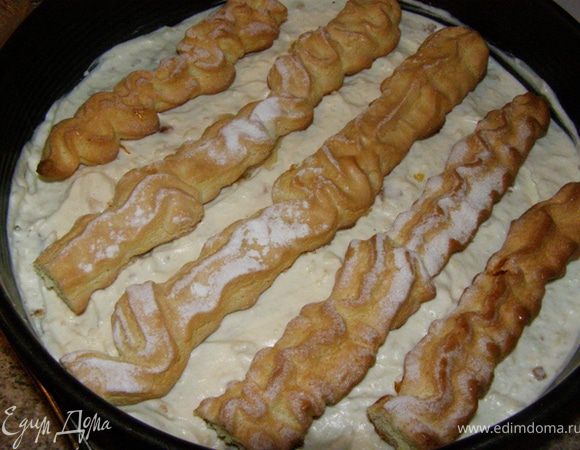 Сверху уложить бисквитные полоски и пропитать их частью пропитки