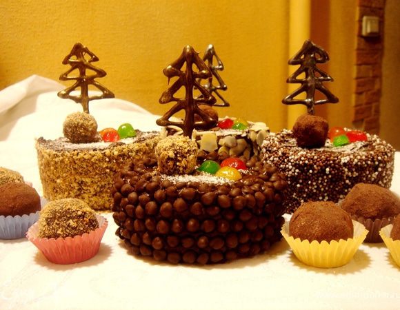Обсыпать края пирожного миндальной крошкой или вафельной крошкой или шоколадными каплями.Ножом сделать прокол в пирожном и вставить в него ёлочку.Украсить пирожное засахаренными фруктами и конфетами,охладить.Оставшиеся конфеты переложить в специальные розеточки и подать отдельно.За час до подачи достать пирожное и конфеты из холодильника.Приятного новогоднего чаепития!