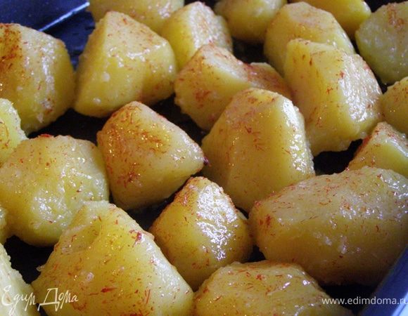 На горячий противень выложим отварной картофель, встряхнем противень, чтобы смешать картофель с маслом. С помощью кисти смажем картофелины шафранным маслом. 