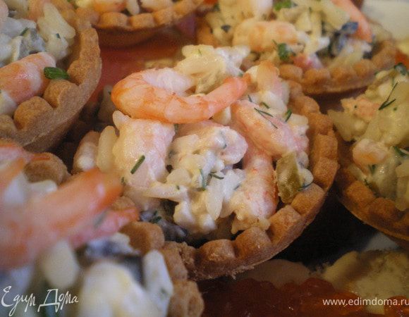 Наполнить тарталетки приготовленным салатом, украсить зеленью и креветками.