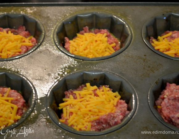 Разделить готовый фарш ровно на 24 порции,выложить по 12 ячейкам наполовину/ у меня форма на 6 порций,размер больше,чем на 12/,сверху на каждую порцию по кубику сыра,закрыть оставшимся фаршем.