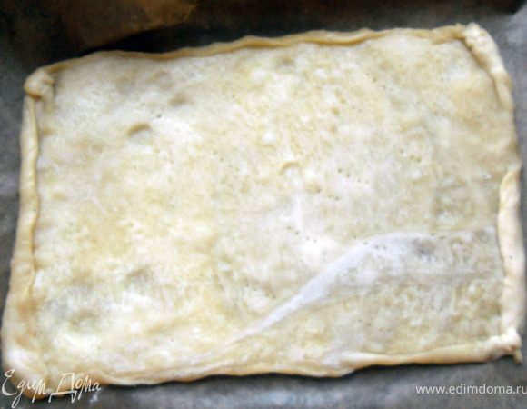 Тесто предварительно разморозить, раскатать не очень тонко, при желании сформировать невысокие бортики. Наколоть вилкой ***далее я предварительно запекал основу около 5 минут, но, полагаю, можно выкладывать начинку сразу***.